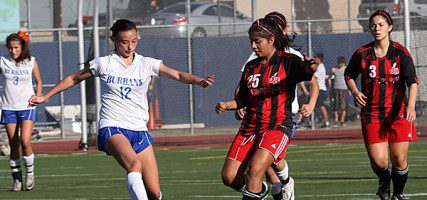 Burbank High's Alessia Dal-Monte takes a kick as Burroughs Alexis Mendias works the field. (Photo by Ross A. Benson)