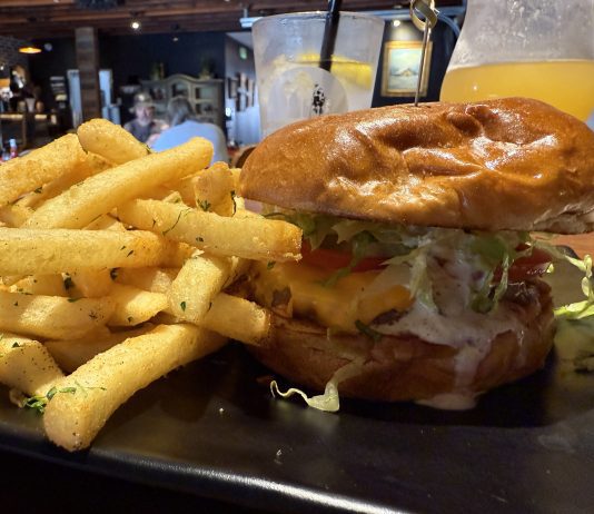 Magnolia Corner Opens With Revamped Space, Solid Bar Menu Magnolia Corner's Classic Beef Cheeseburger is topped with cheddar cheese, cocktail sauce, tzatziki, grilled onions, lettuce and tomato and accompanied by fries seasoned with parsley, salt and pepper.