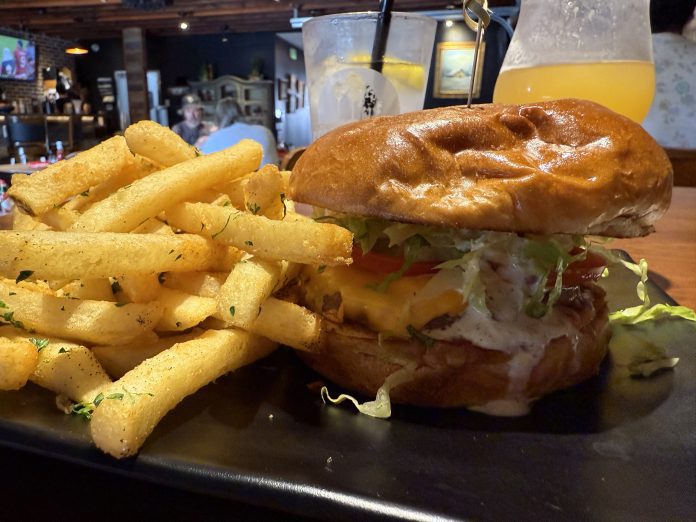 Magnolia Corner's Classic Beef Cheeseburger is topped with cheddar cheese, cocktail sauce, tzatziki, grilled onions, lettuce and tomato and accompanied by fries seasoned with parsley, salt and pepper.