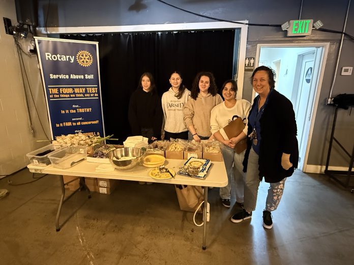 Five volunteers stand before an array of food at the Burbank VFW