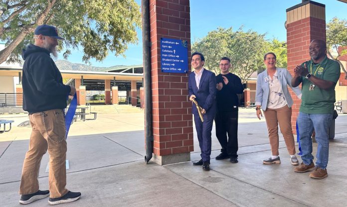 burbank-high-school-wayfinding-event Two students and three school officials smile as they use large scissors to cut a ribbon in front of a new campus wayfinding sign at Burbank High School.